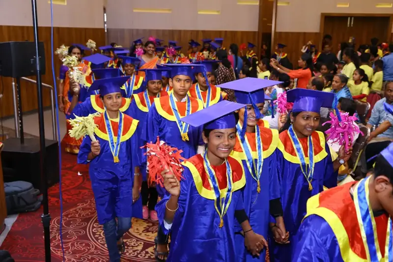 Children in graduation caps celebrating on stage with certificates